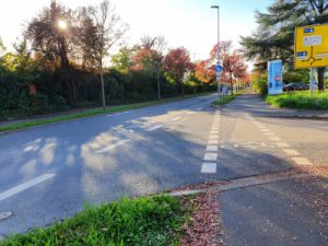 Sharrows verdeutlichen die Fahrbahnnutzung durch Radverkehr, der Gehweg ist zusätzlich zum Radfahren in SCHRITTGESCHWINDIGKEIT freigegeben. Hier sind zusätzliche Piktogramme Fußgänger in der Furt sinnvoll.